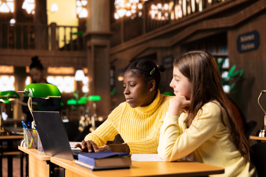 Two students collaborating on a laptop in a school library